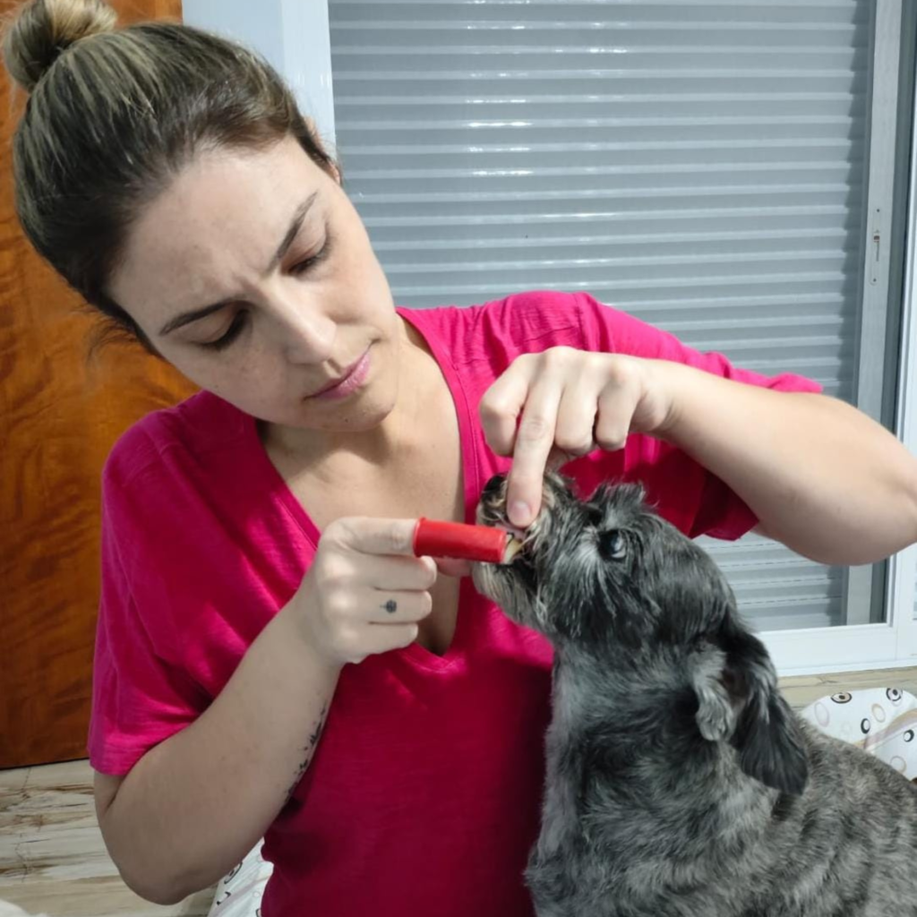 A tutora Juliana Bonetto escova os dentes de um dos seus cães usando dedeira (Crédito: Arquivo pessoal)
